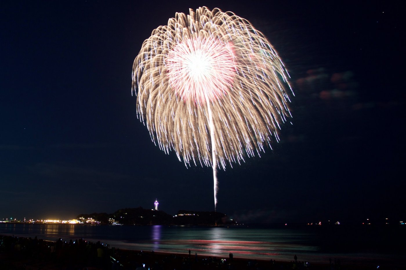 Fireworks bursting over the sea with Enoshima and the Enoshima Sea Candle in the background